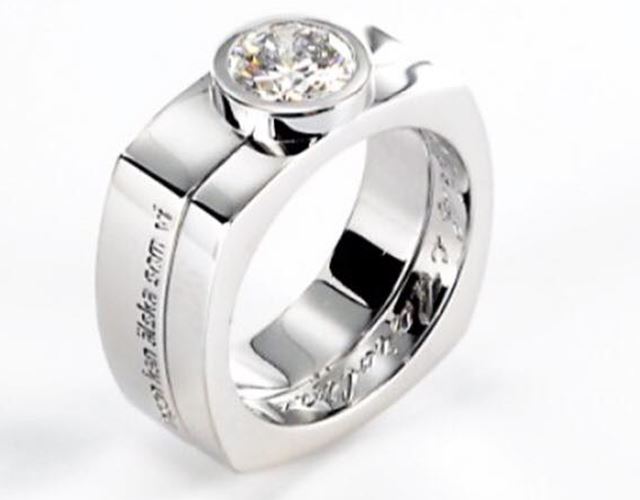Specialdesignad ring i vitguld med briljantslipad diamant, med välvd fyrkantig form, maskinfräst sidgravyr och handgraverad insida, anpassad för att fungera tillsammans med befintlig ring.